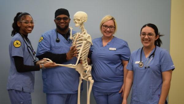 A group of medical professionals posing with a skeleton